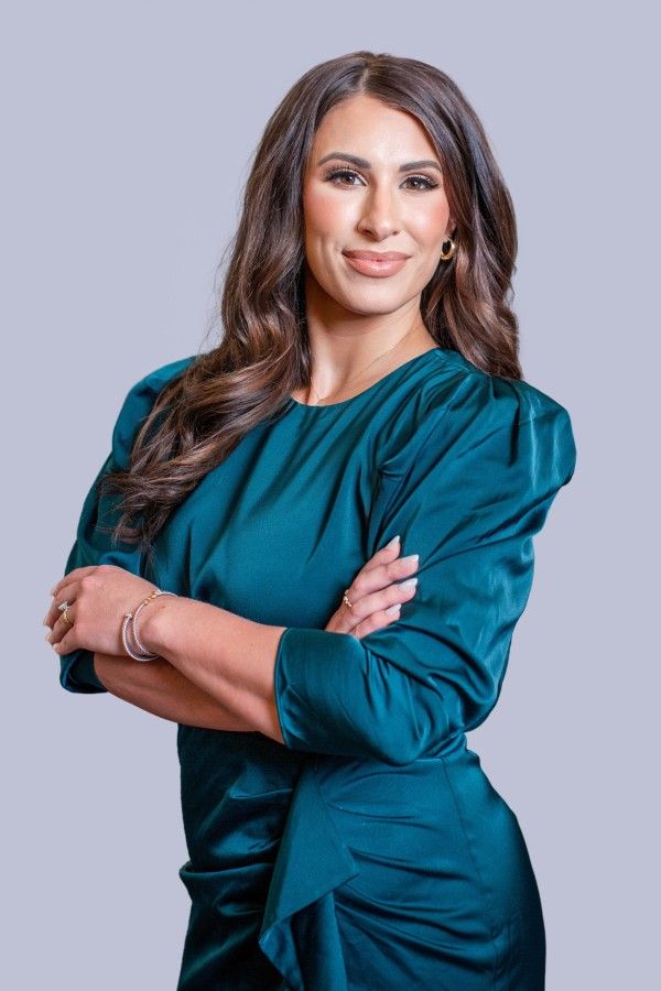 Professional woman in teal dress posing confidently.