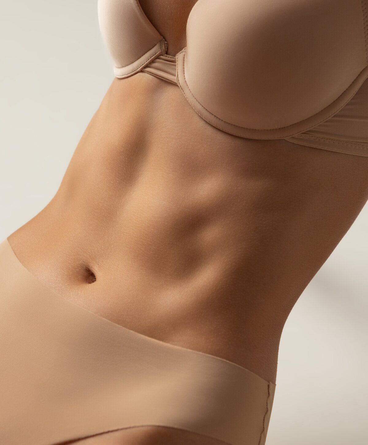 Close-up of abdomen in beige lingerie.