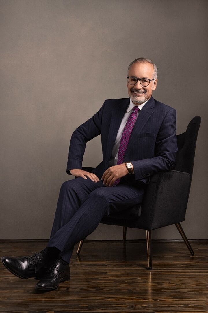 Man in formal attire sitting on a chair.