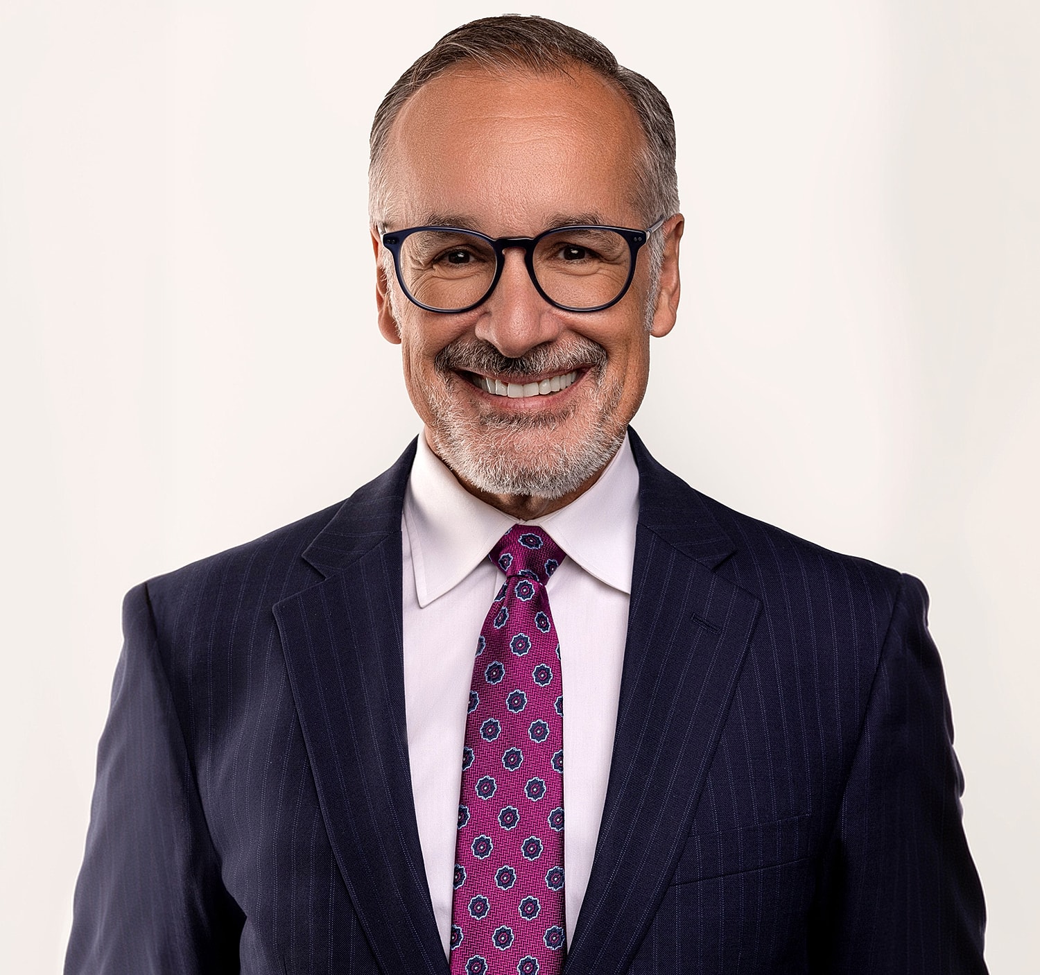 Smiling man in suit and glasses, professional portrait.