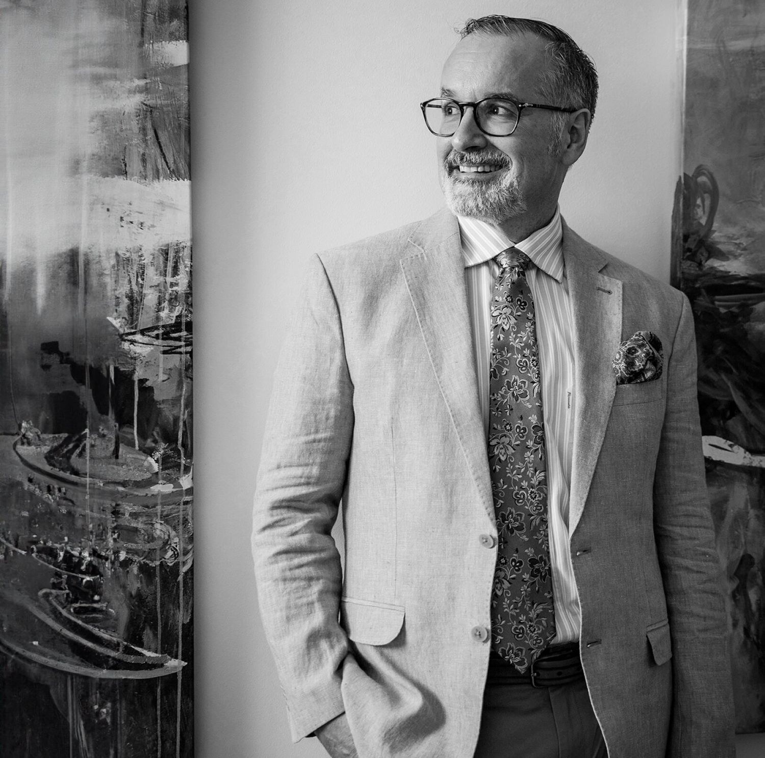 Paul Fortes in a suit, smiling beside abstract art.