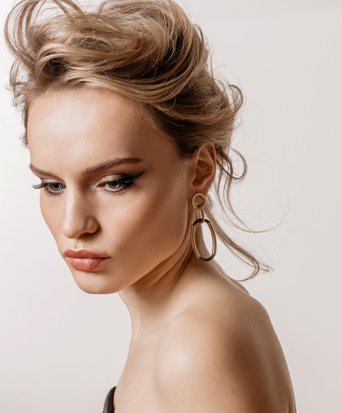 Facelift model with elegant hairstyle and statement earrings.