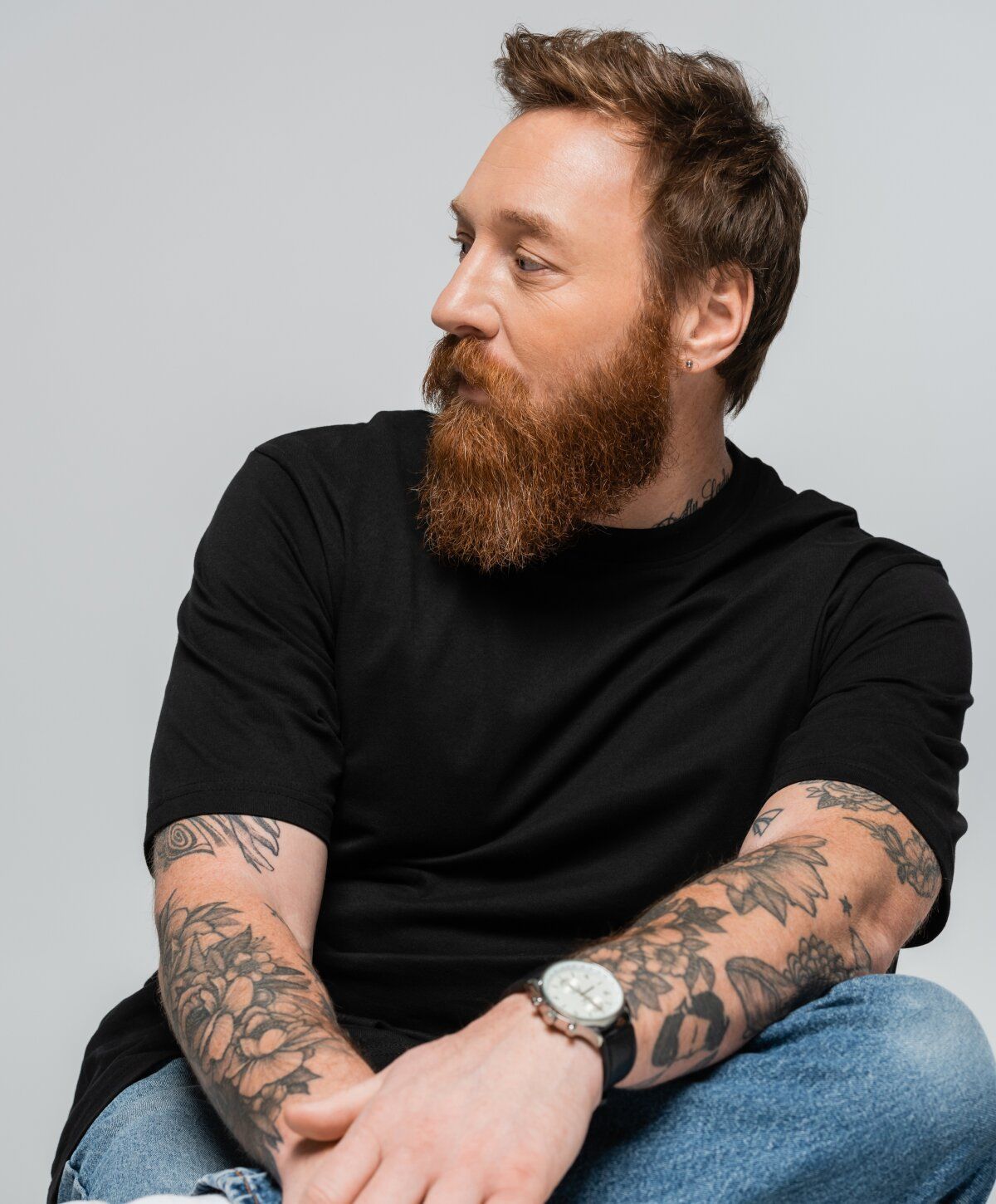 Man with tattoos and beard, wearing black shirt.