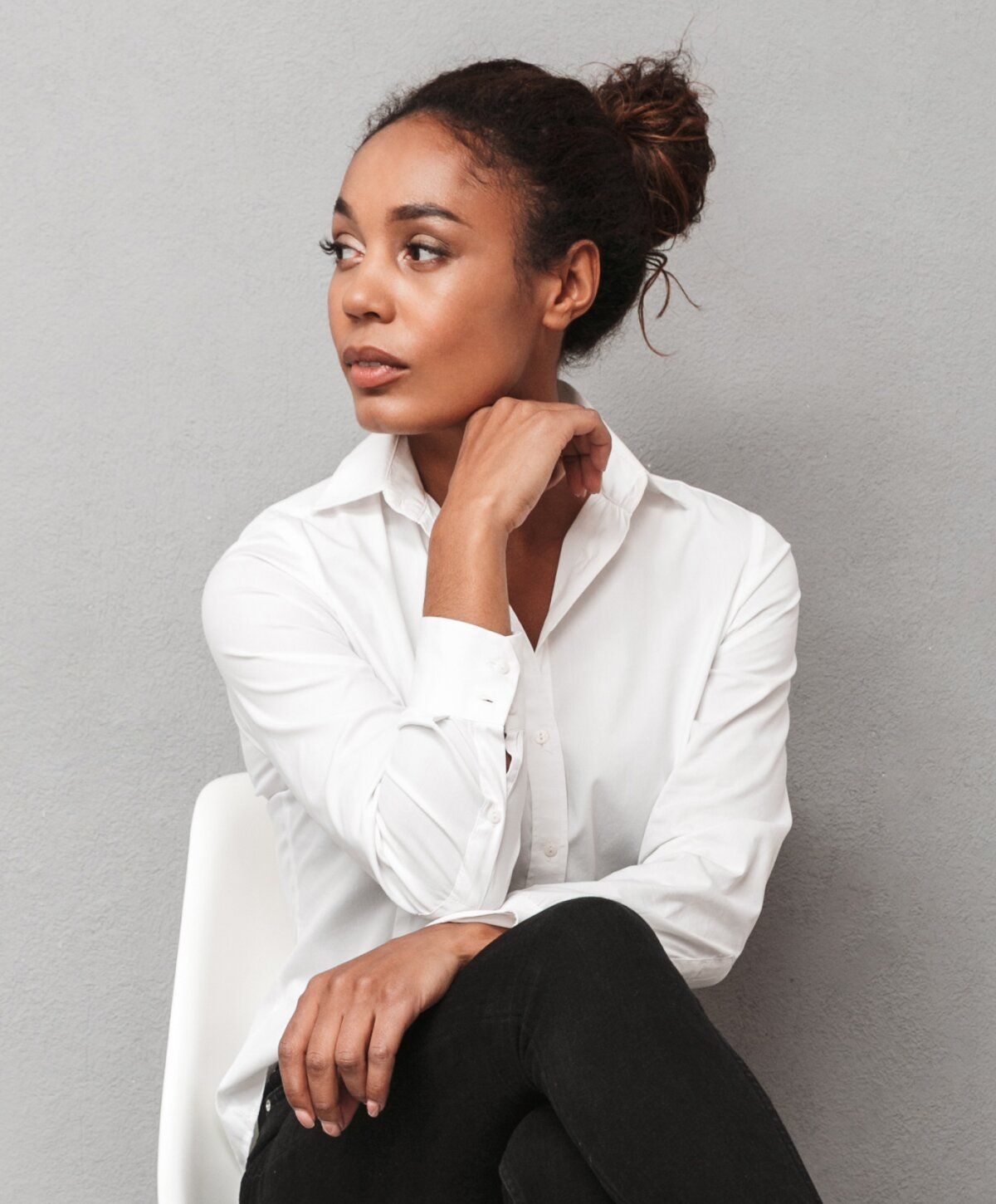 Woman in white shirt, touching her chin thoughtfully.