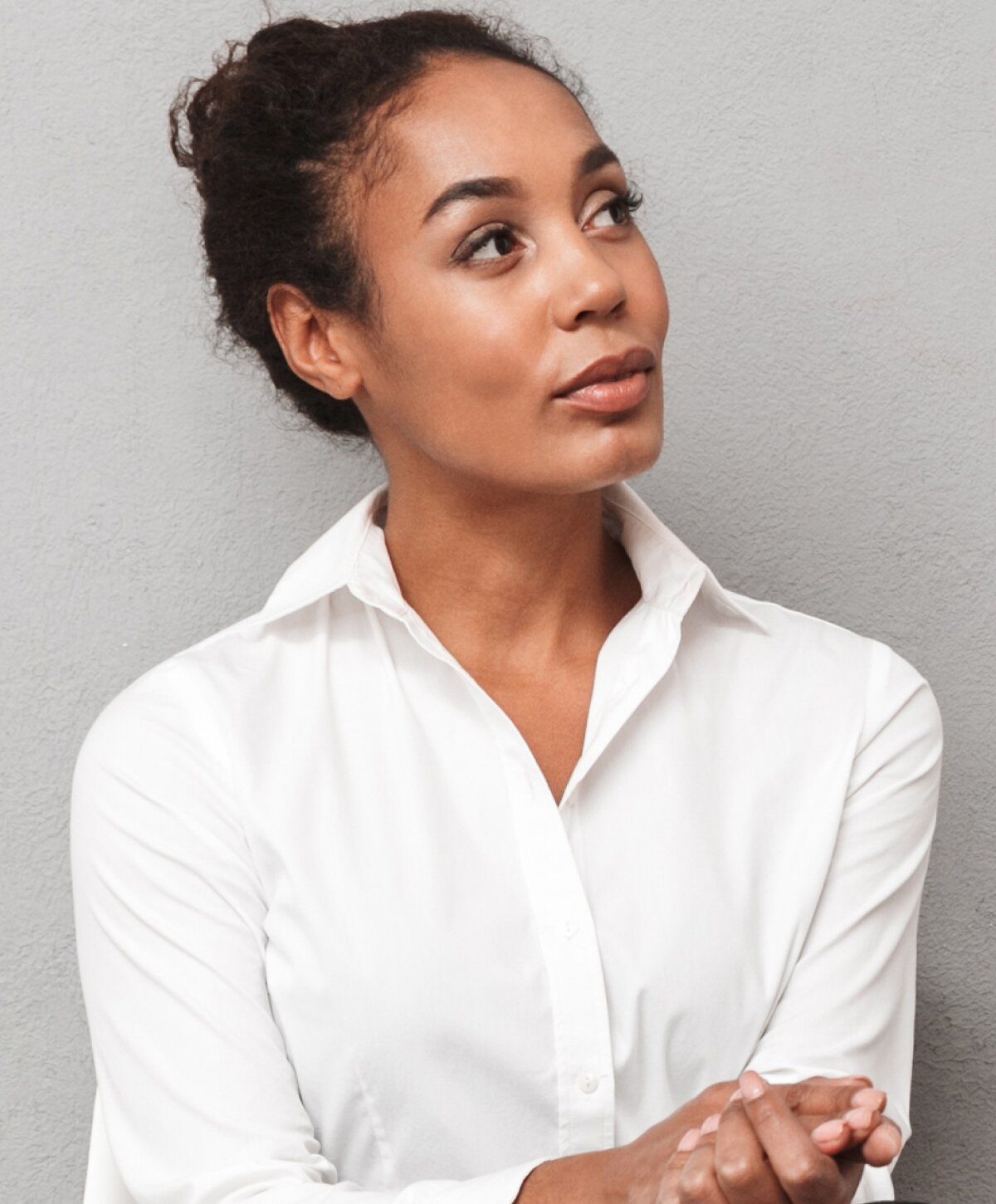 Woman in a white shirt looking thoughtfully upward.