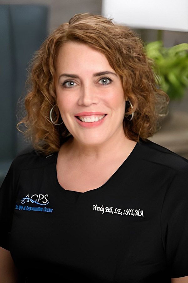 Smiling woman in medical scrubs, professional setting.
