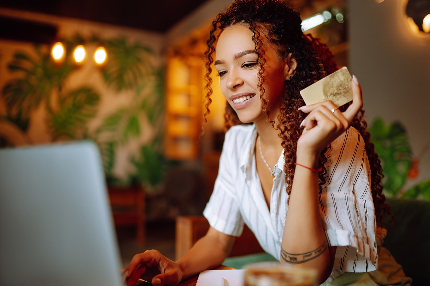 Woman shopping online with credit card in hand.