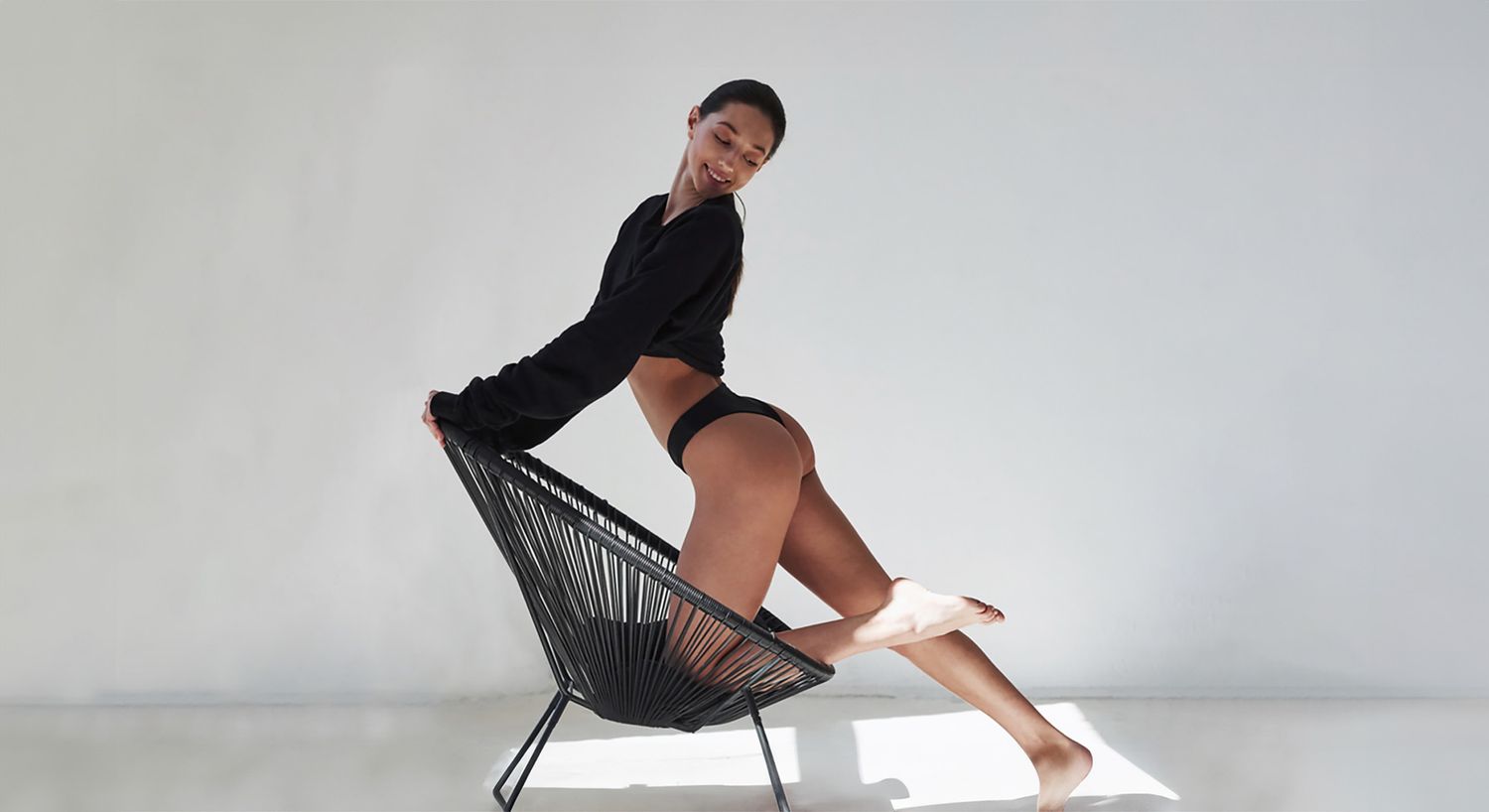 Aveli model posing playfully on a chair.
