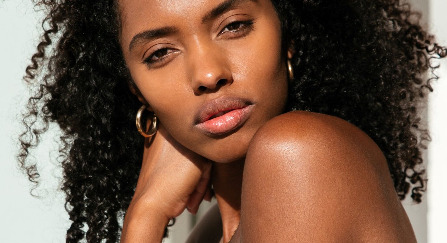Close-up of lip lip model with curly hair and earrings.