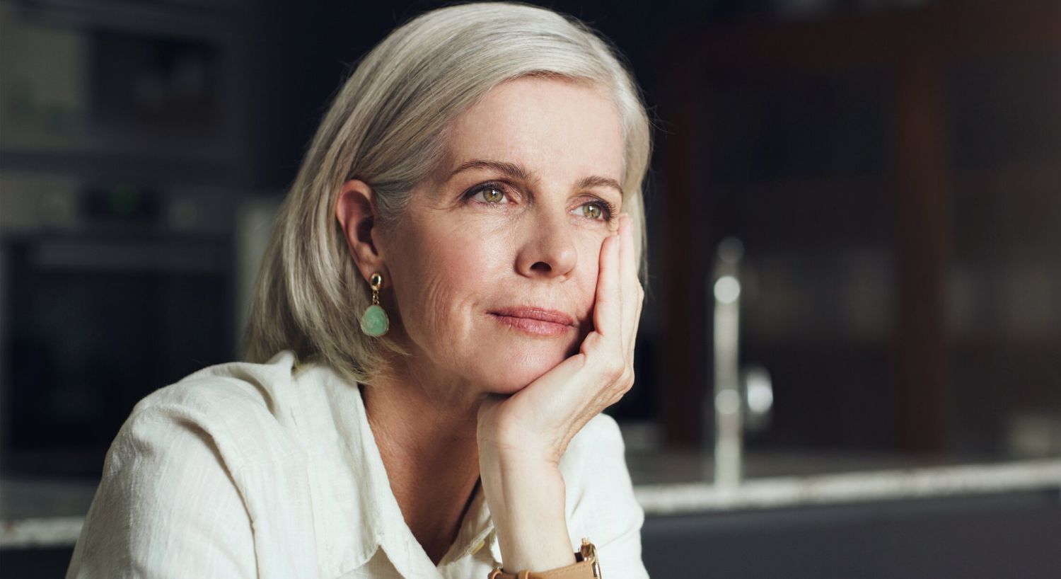Thoughtful woman with short gray hair indoors.