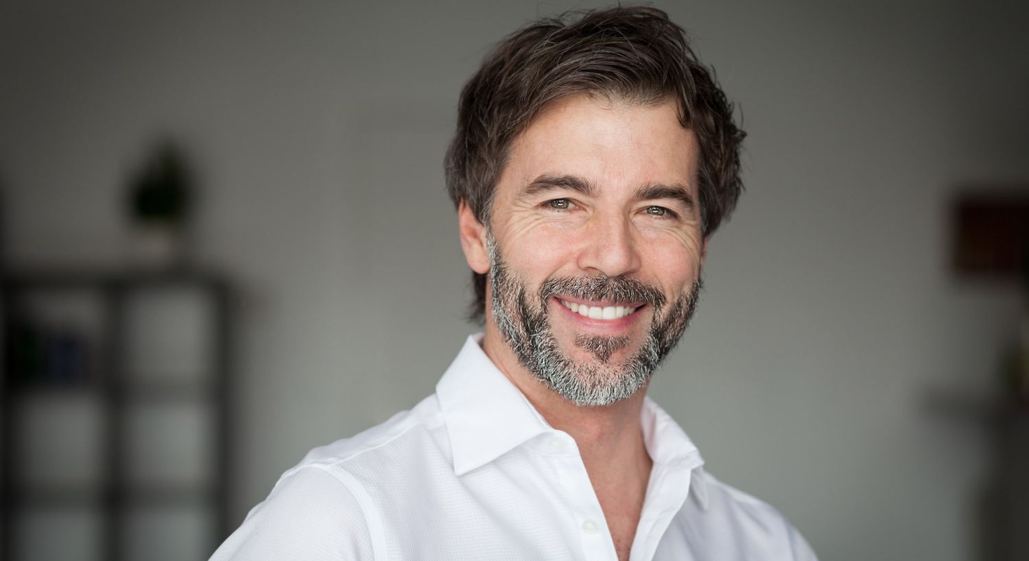 Smiling man with beard in white shirt.